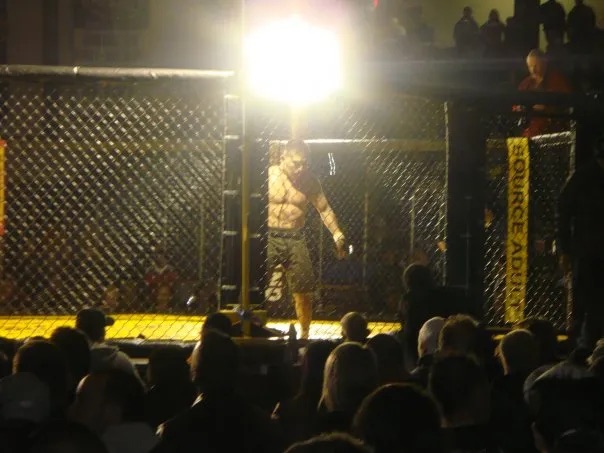 Mixed martial arts bout in a cage, viewed from the audience.